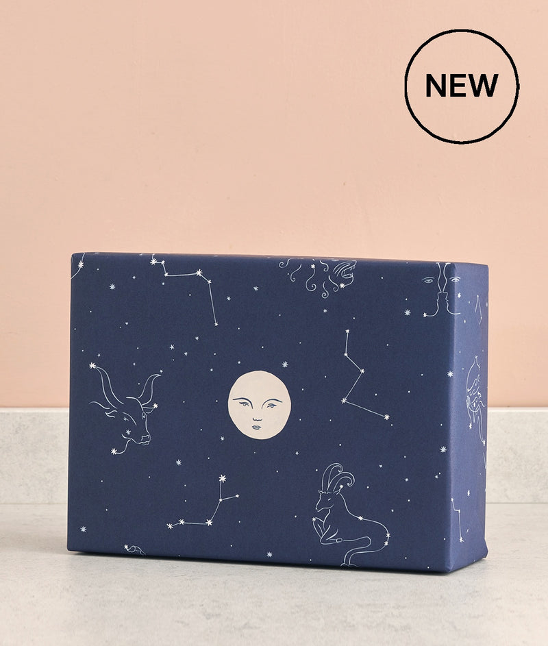 constellations on a dark blue background with stars and a stylish moon on this luxury wrapping paper at Crane and Kind for unique gifts